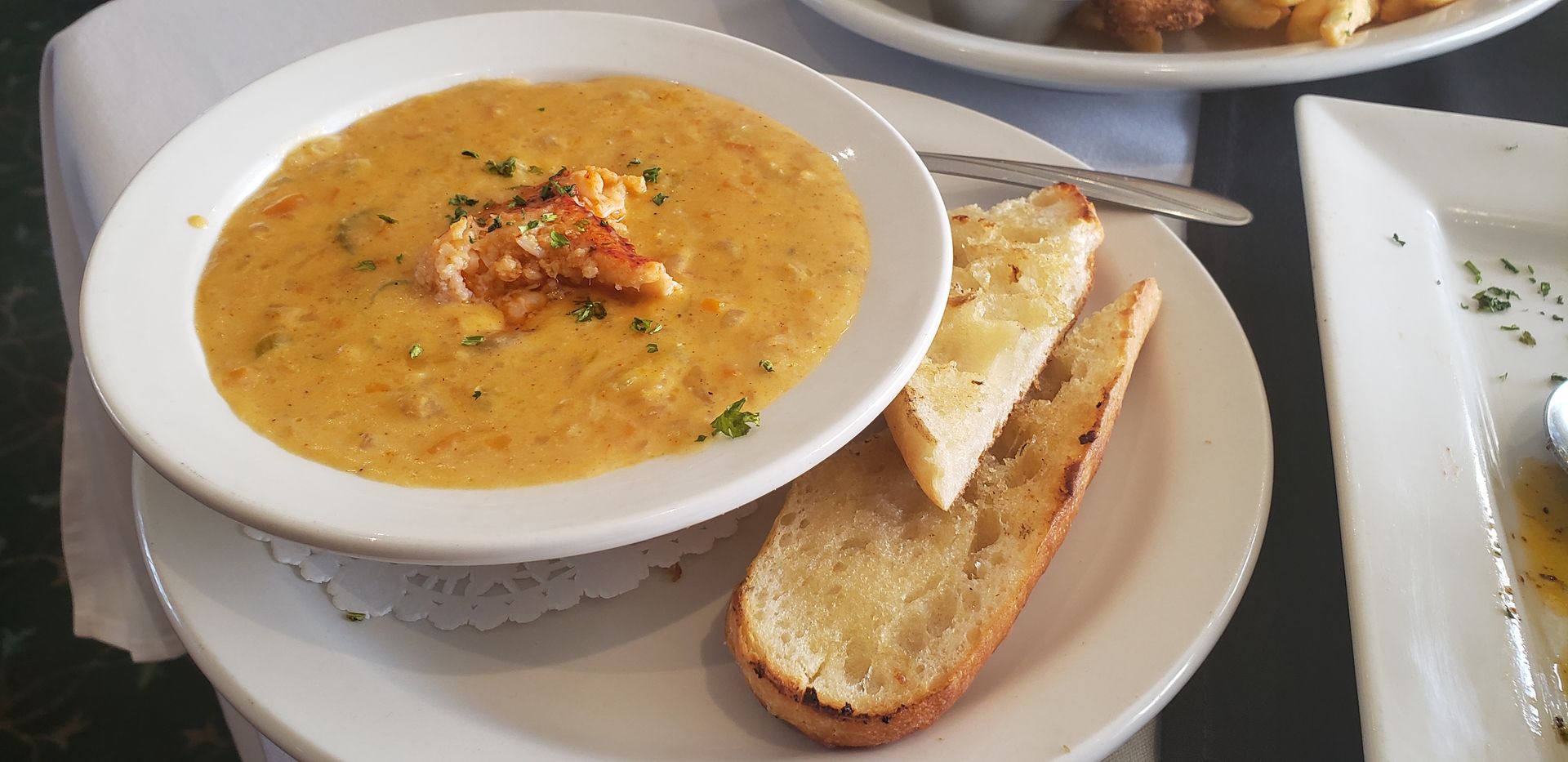 a bowl of soup with garlic bread on a plate .