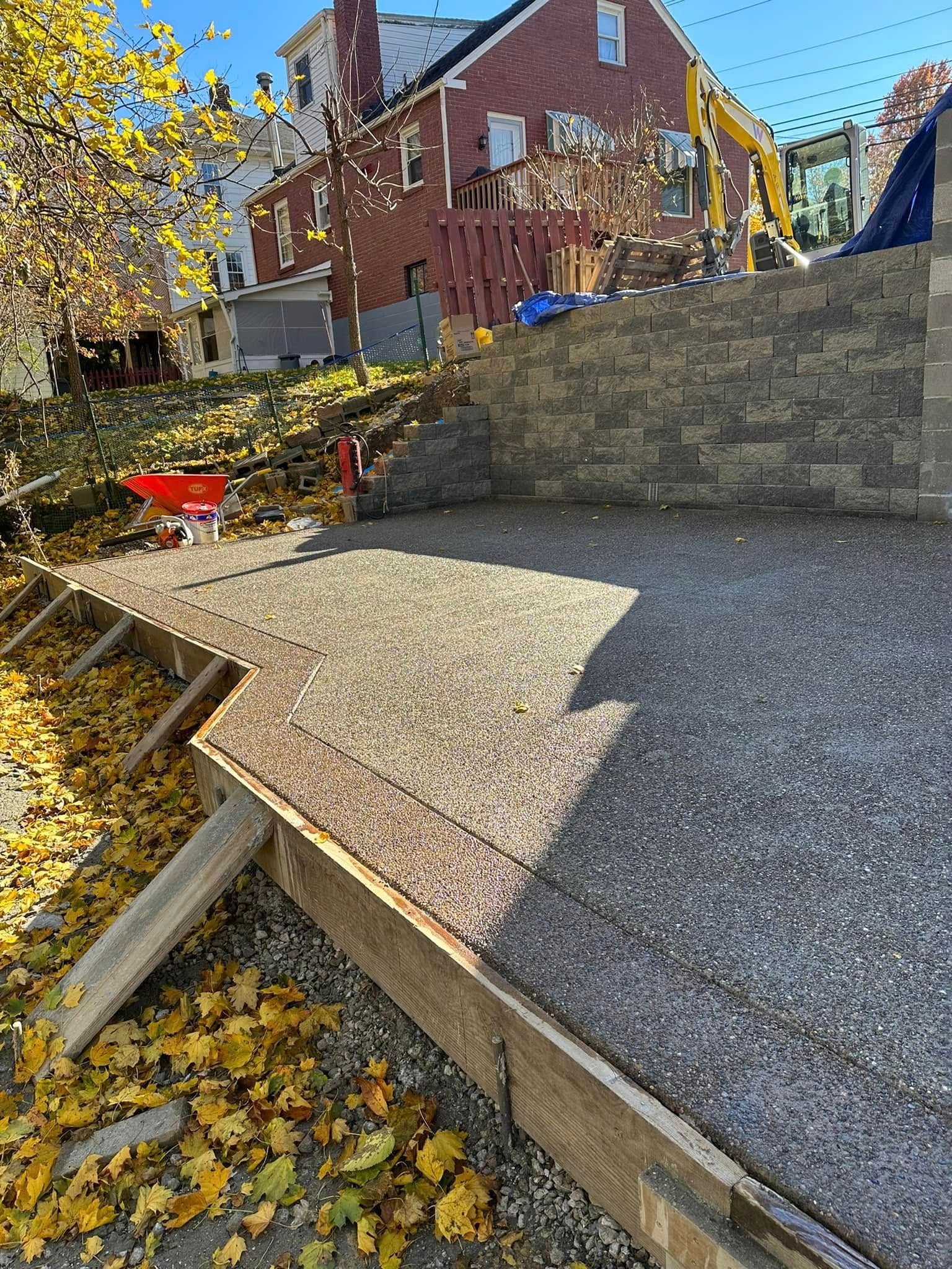 Concrete ramp and steps beside a brick house with fallen autumn leaves and a red wheelbarrow
