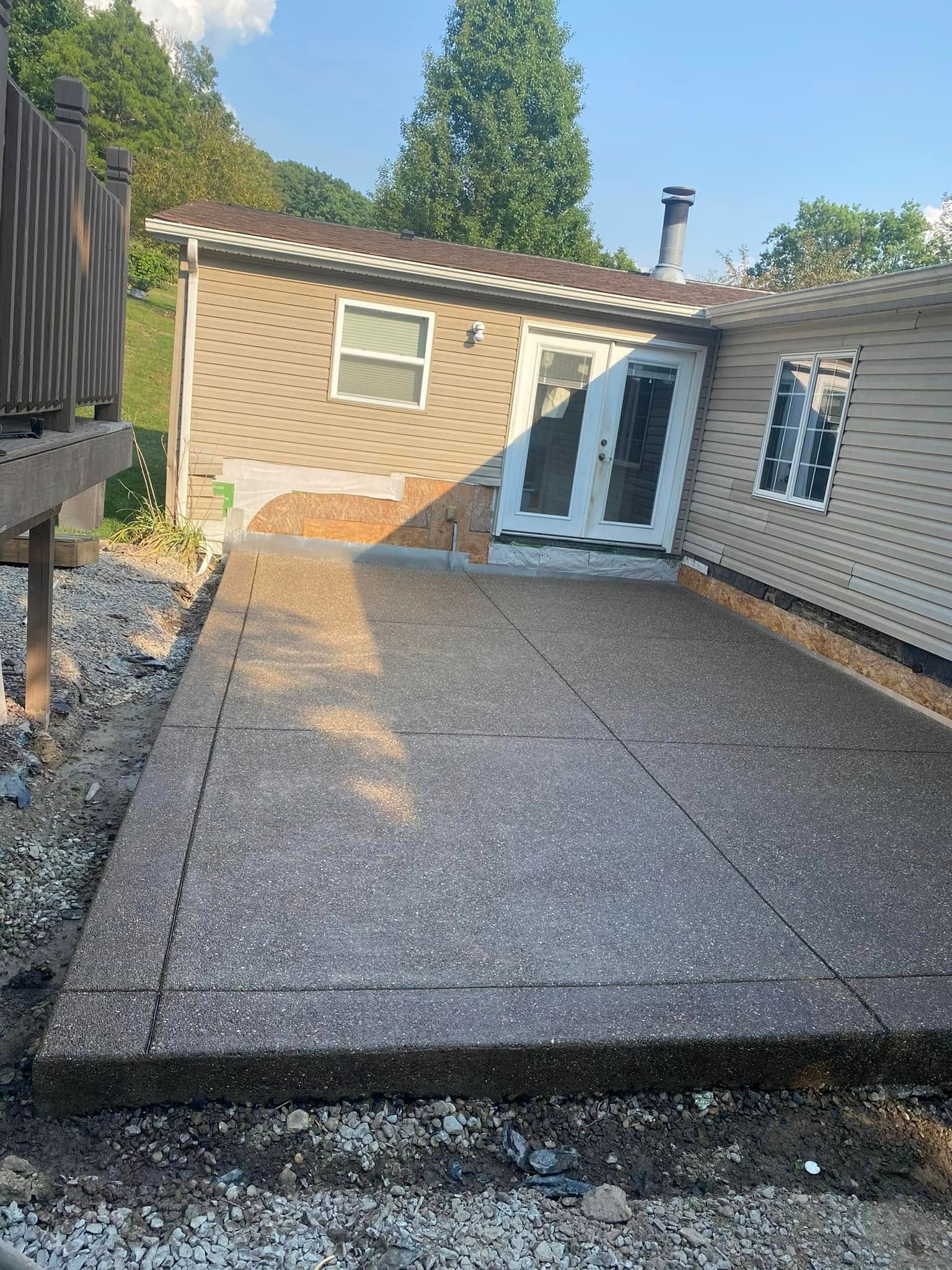 Backyard concrete patio beside a tan house with white French doors and a small window
