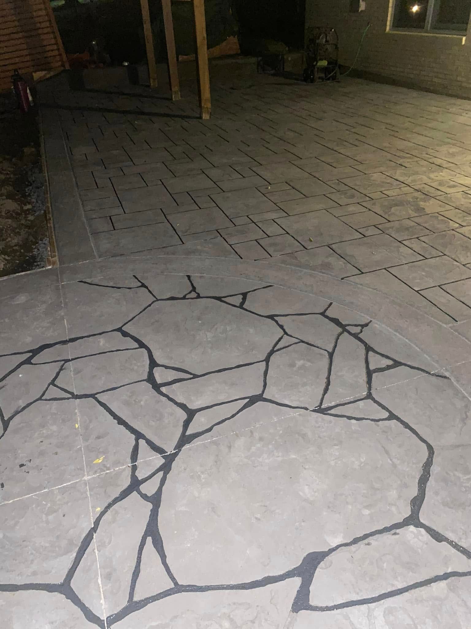 Cracked concrete walkway at night under dim lighting with a brick building in the background