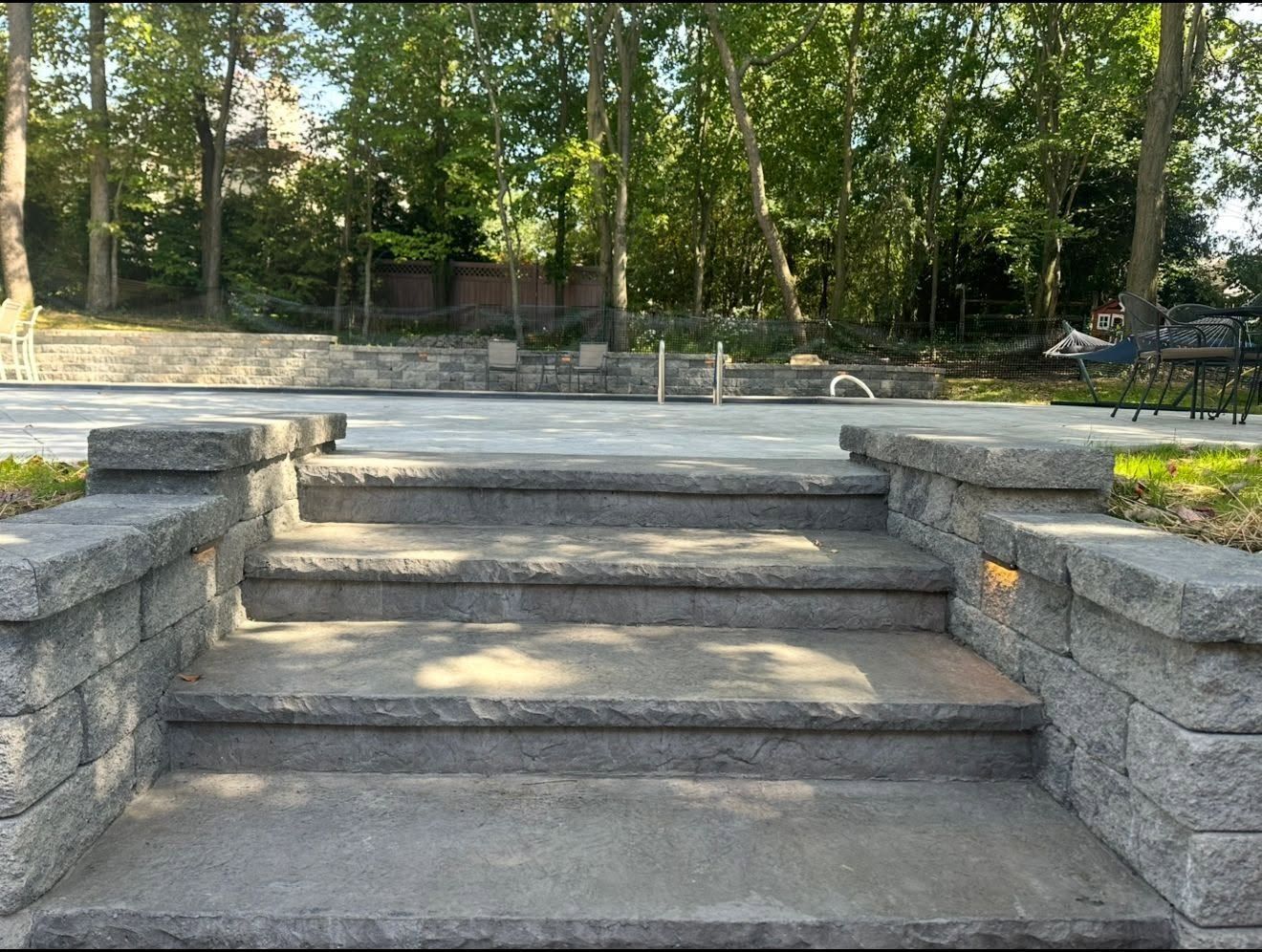 Stone steps leading to a tree-lined park path with benches in the background