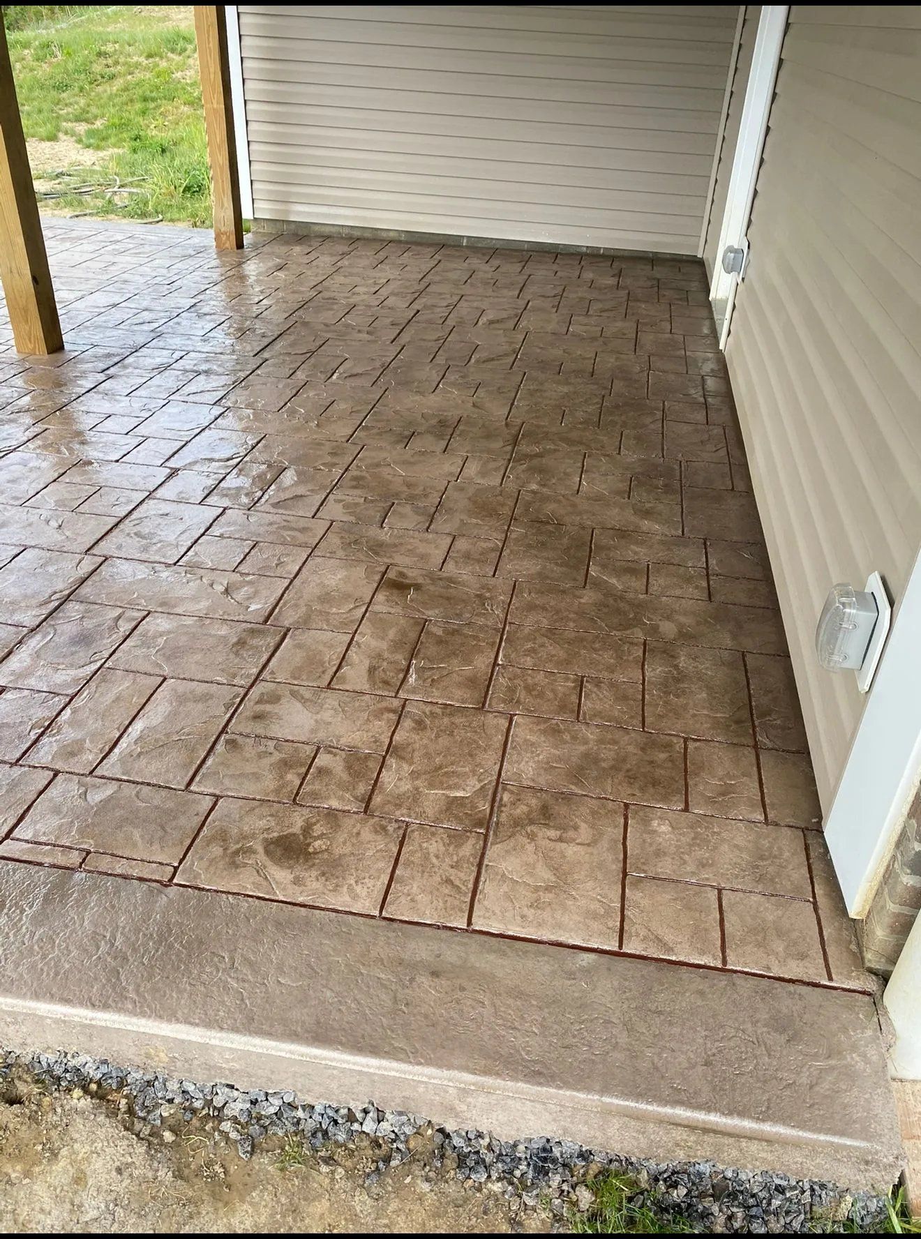 Covered porch with stamped concrete floor and beige siding; no people visible