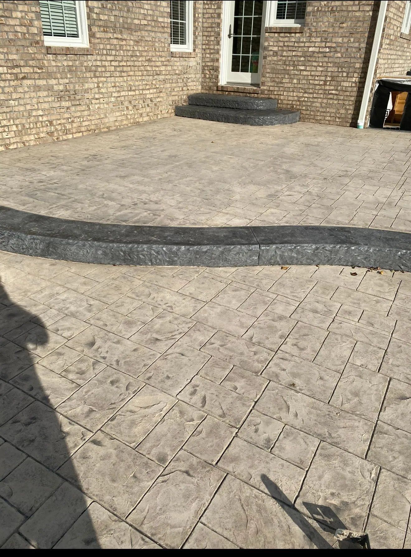 Brick patio with patterned paving, a low step, and a house entrance in the background