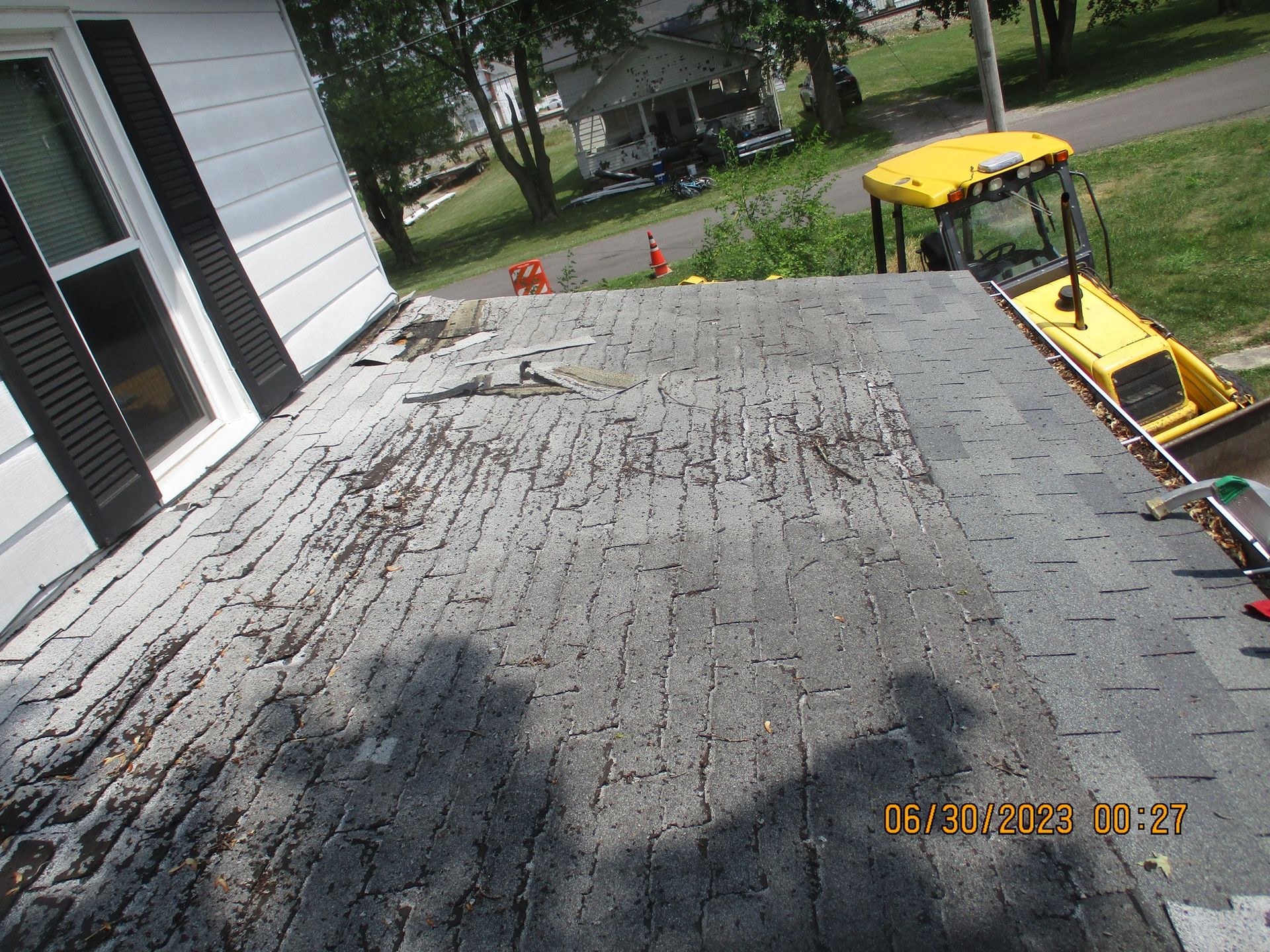 A yellow tractor is sitting on the roof of a house.