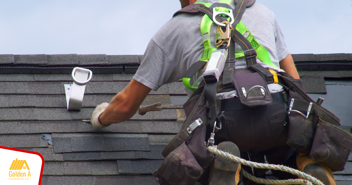 A man wearing a harness is working on a roof.
