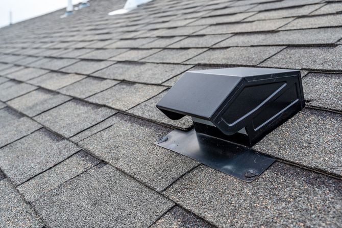 A black roof vent is sitting on top of a roof.