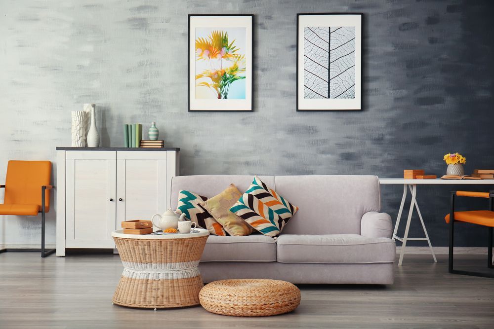 Living room with gray sofa, colorful pillows, two framed art pieces, and a round coffee table.