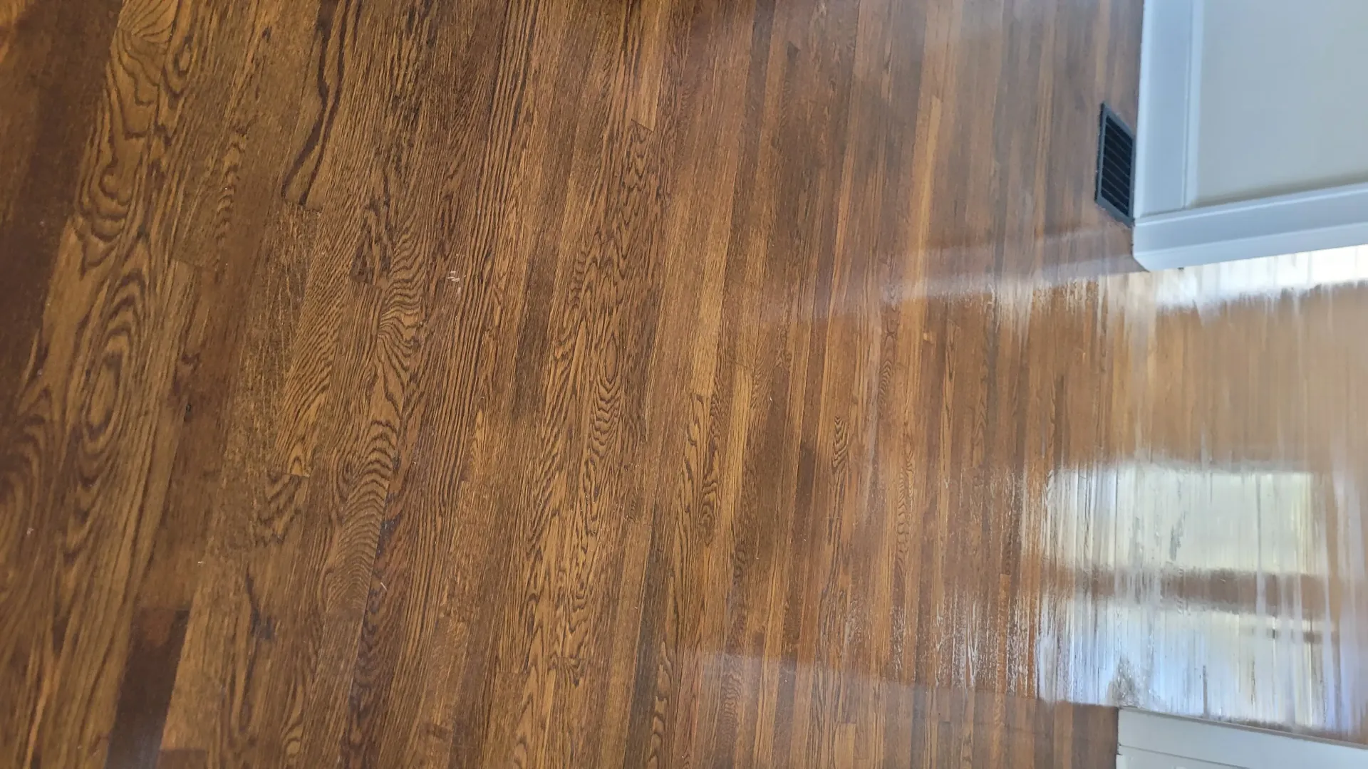 Wooden floor being cleaned; a white cabinet is visible on the right.
