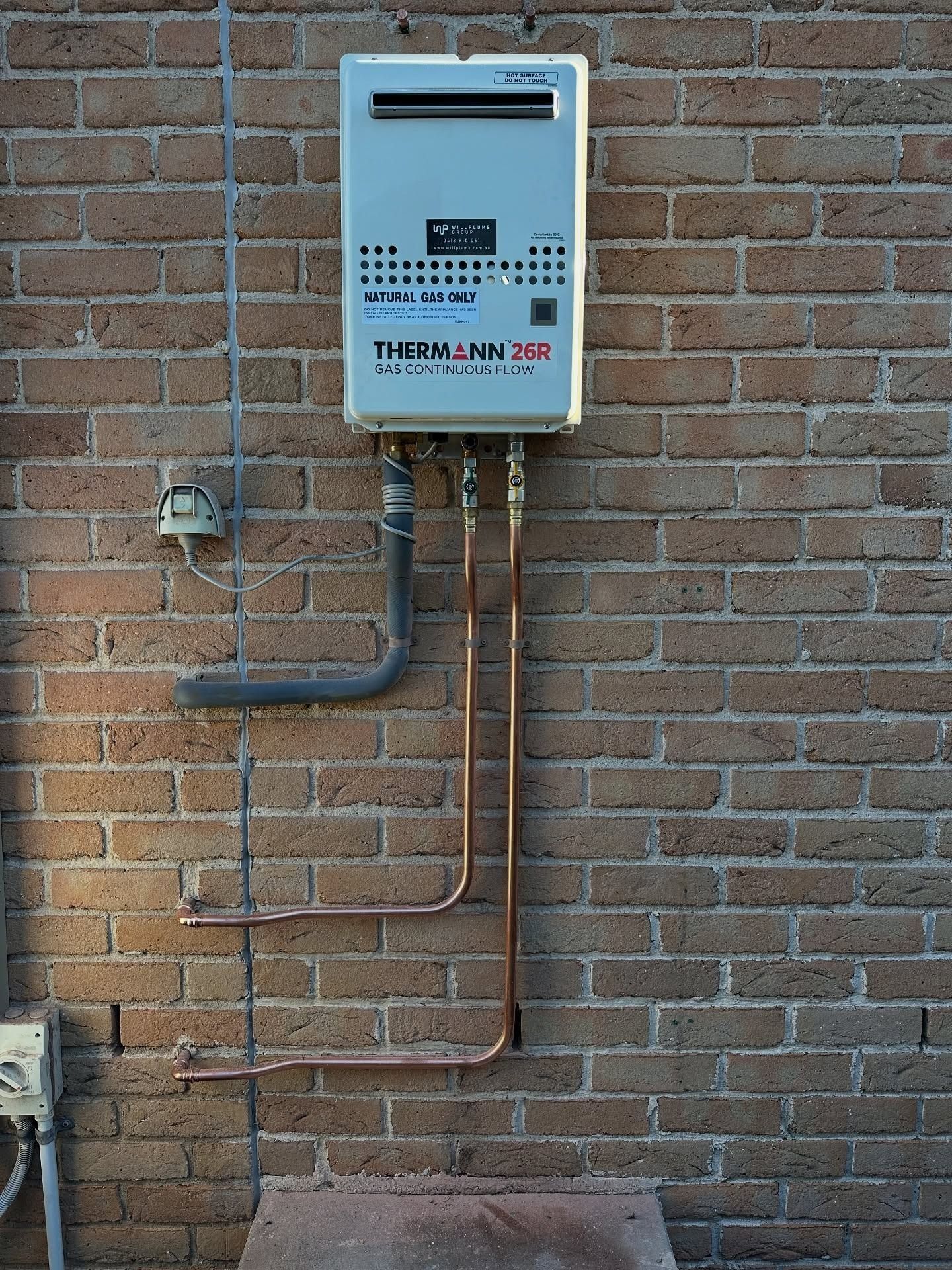 Wall-mounted gas heater and pipes on a brick exterior wall