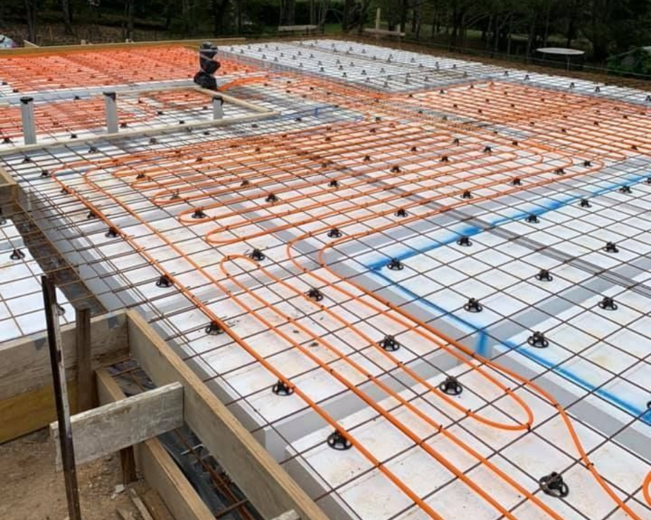 Construction site with orange rebar grid laid over a concrete slab foundation