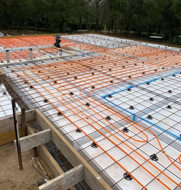 Rebar and orange tubing laid over white insulation on a construction foundation slab