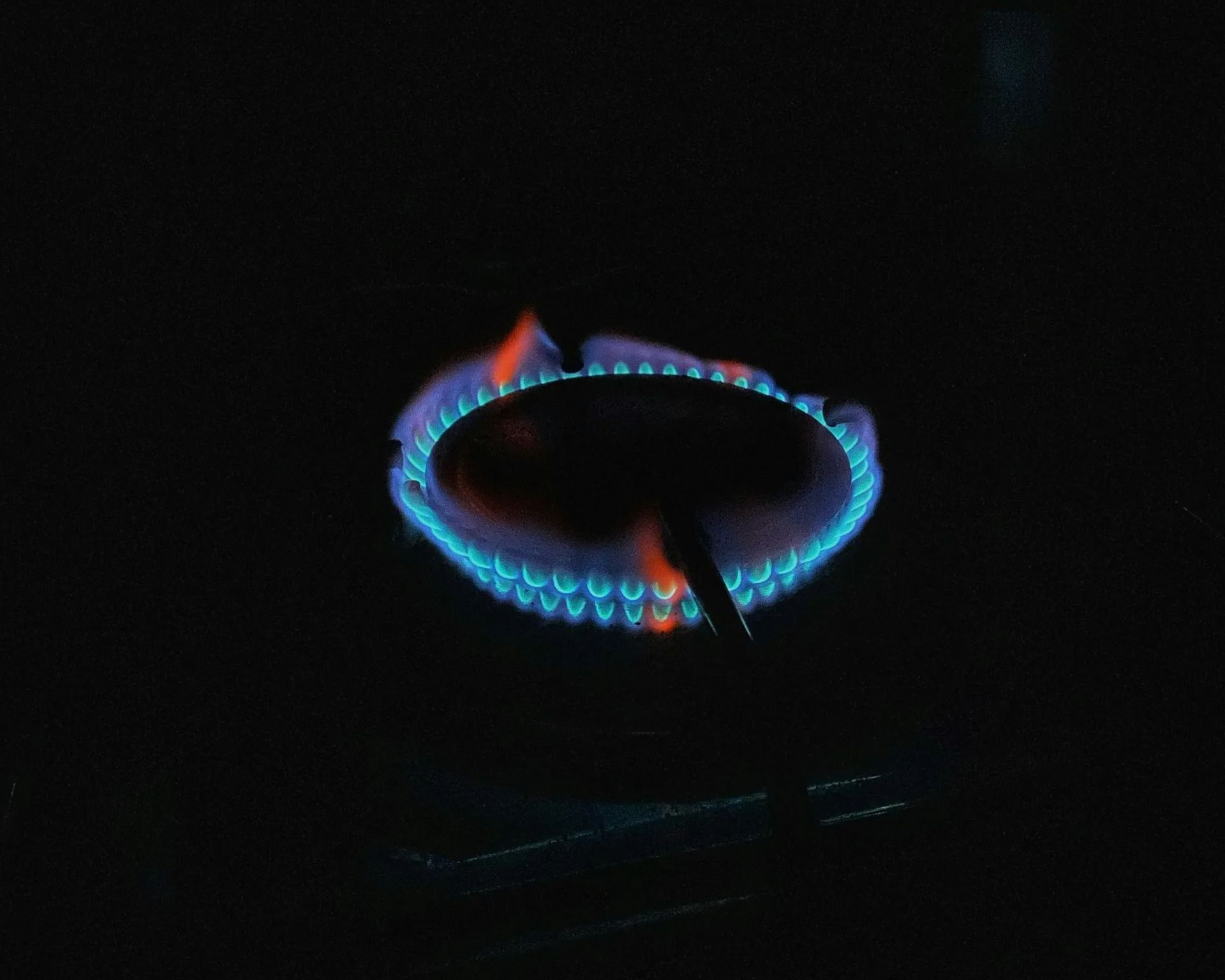 Blue-orange gas stove burner flame in a dark setting