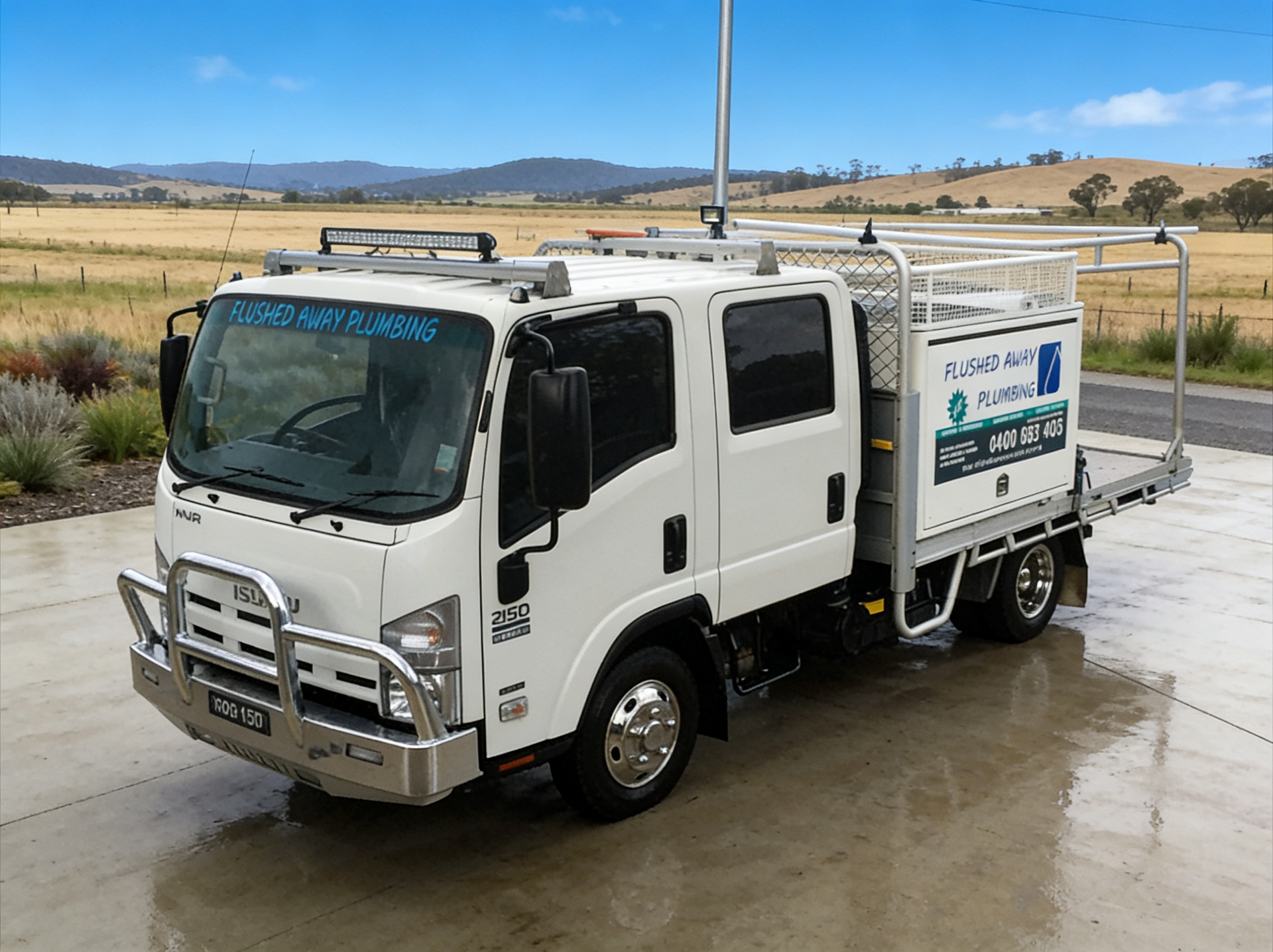 White utility truck parked on a wet road beside open fields under a cloudy sky