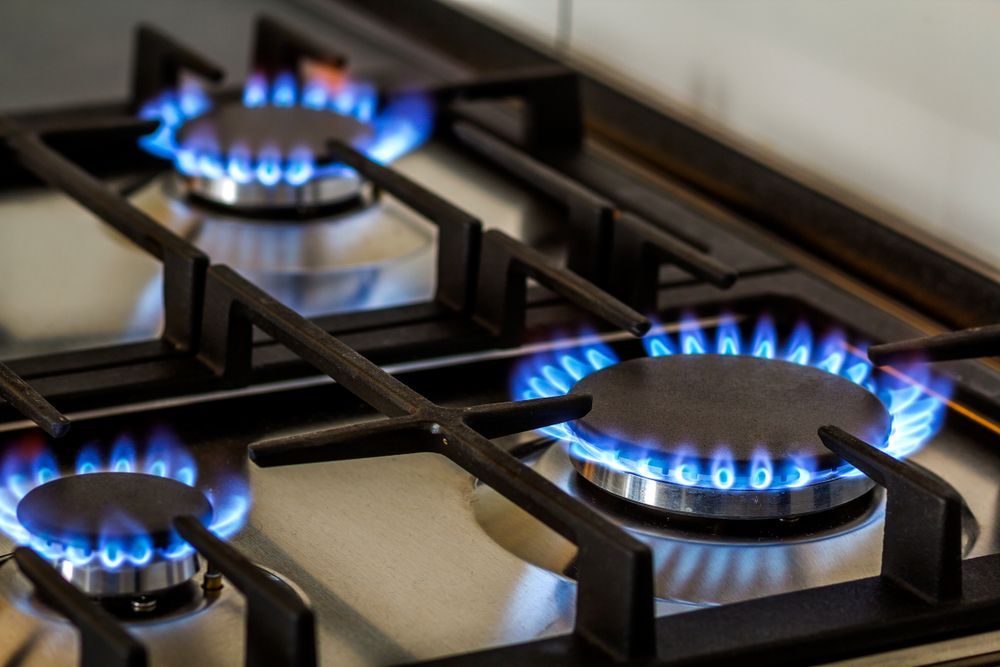 Close-up of a gas stovetop with three lit blue burners