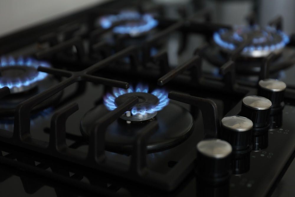 Gas stove burners lit with blue flames on a black cooktop
