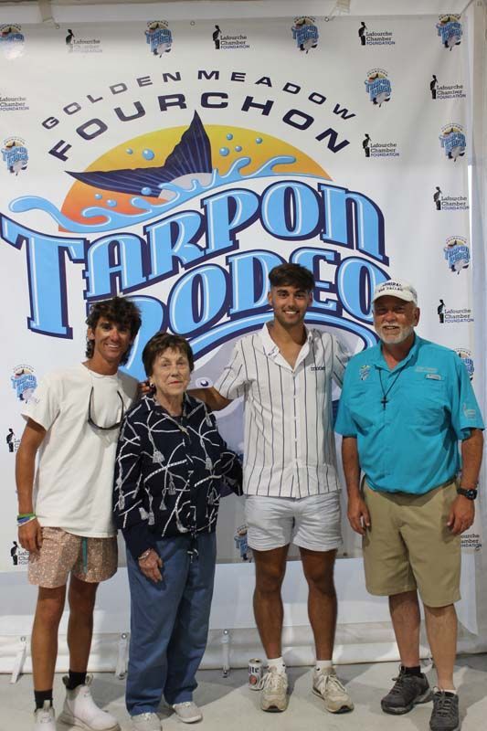 A group of people standing in front of a banner that says tarpon rodeo