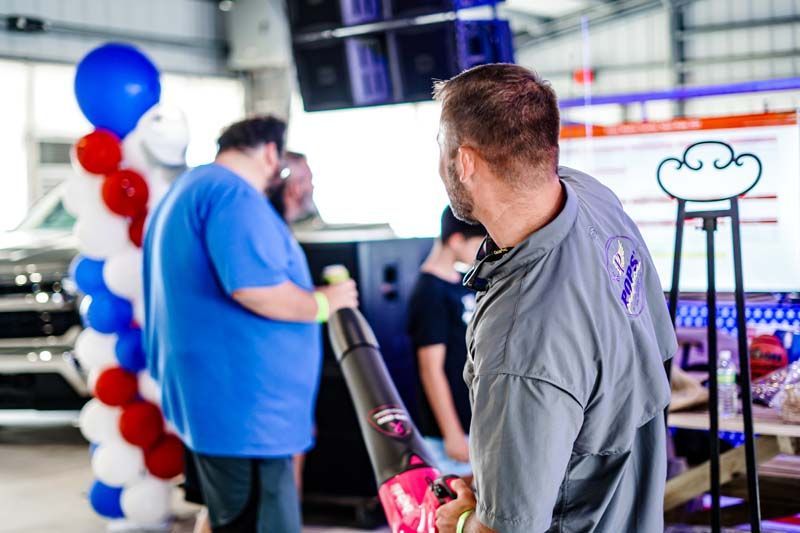 A man is standing in a garage holding a vacuum cleaner.