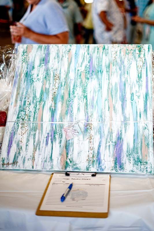 Abstract pastel painting on an easel with a clipboard and pen in front, at a table outdoors