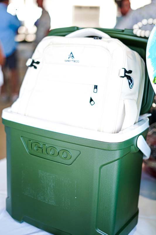 White infant car seat in a green storage bin, with blurred people in the background