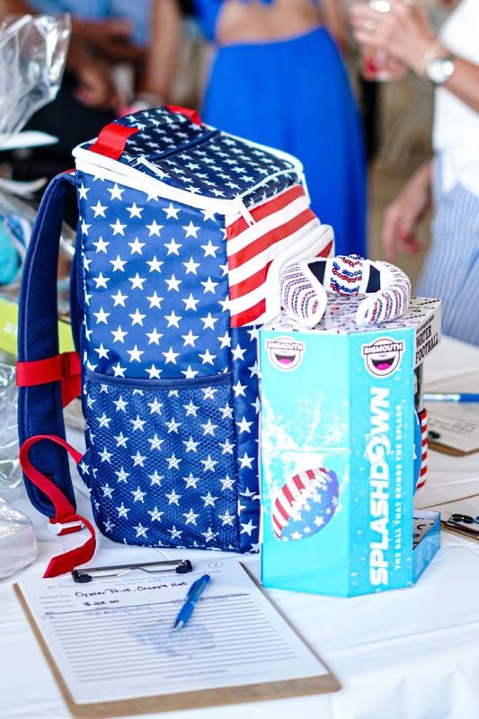American flag-patterned gift bag and pastel box on a table with a sign-in sheet and pens