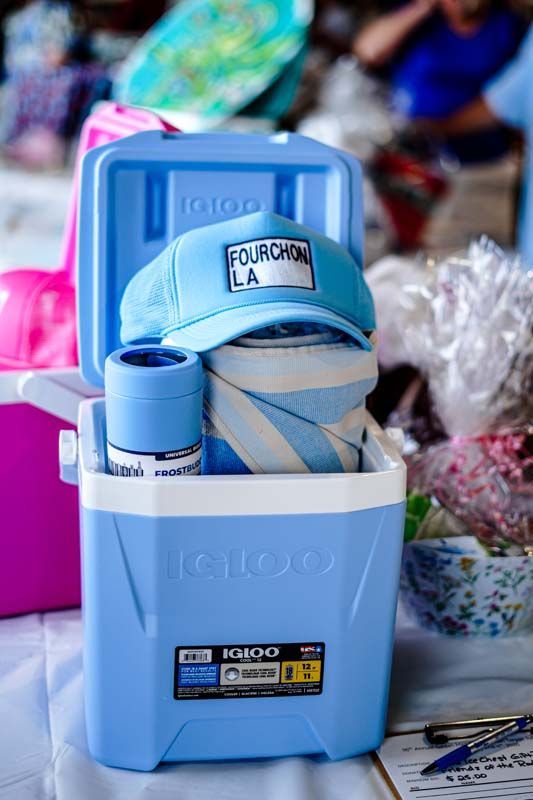 Blue cooler filled with folded clothes and a cap at an outdoor market stall