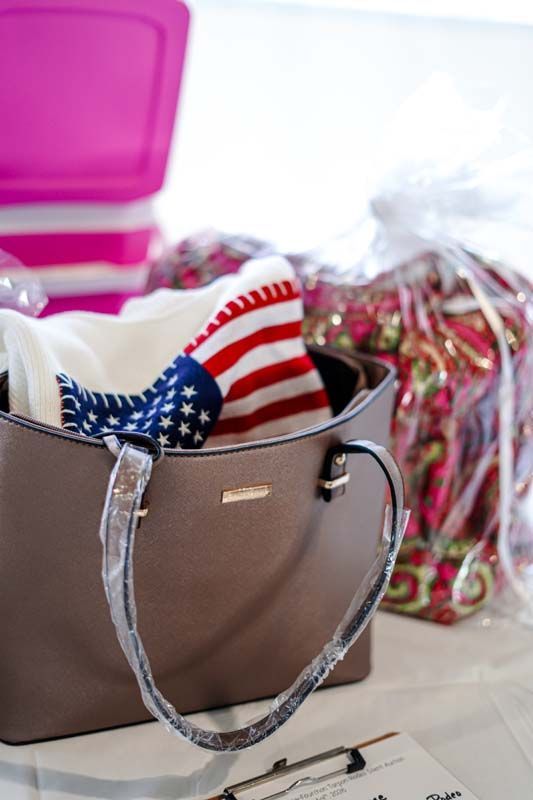 Brown handbag with an American flag scarf, beside a pink container and colorful holiday decorations