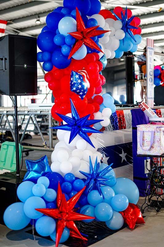 Red, white, and blue balloon column with star decorations in an indoor event space