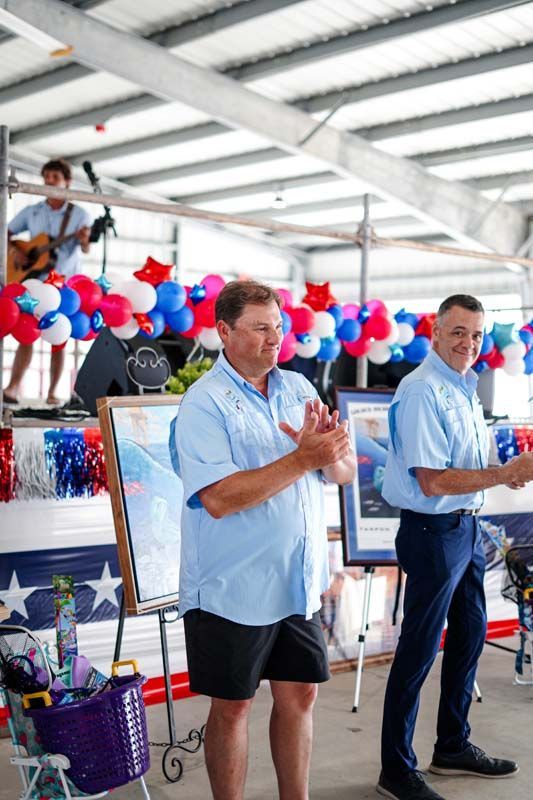 People clapping at a patriotic indoor event with red, white, and blue decorations