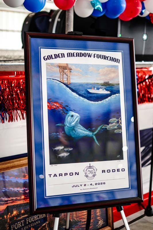 Framed Golden Meadow tournament poster with fish illustration, red-white-blue balloons above and tinsel backdrop