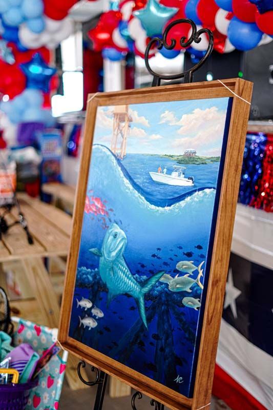 Framed ocean painting with a sea turtle and boat, displayed amid red, white, and blue balloons
