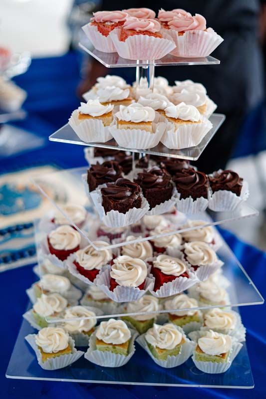 Tiered dessert stand with assorted cupcakes topped in pink, white, chocolate, and green frosting