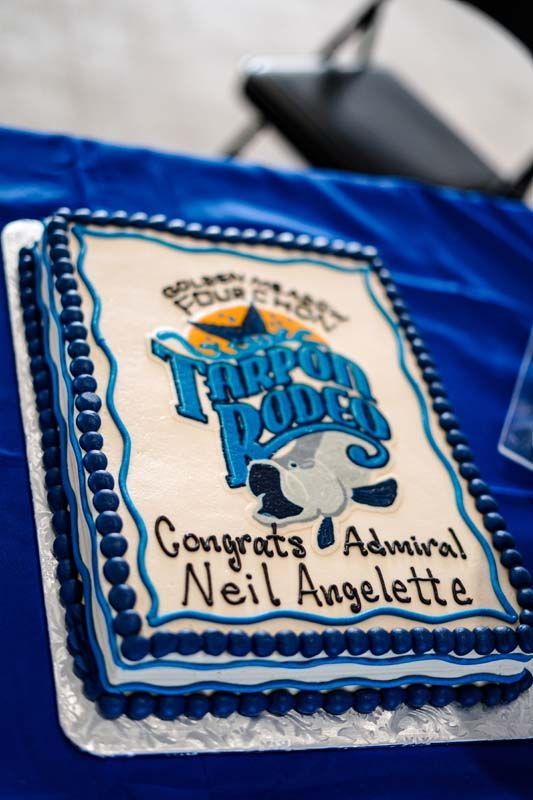 Blue-and-white cake with a “Happy Roots” logo and “Congrats Admiral Neil Angeletti” written on top