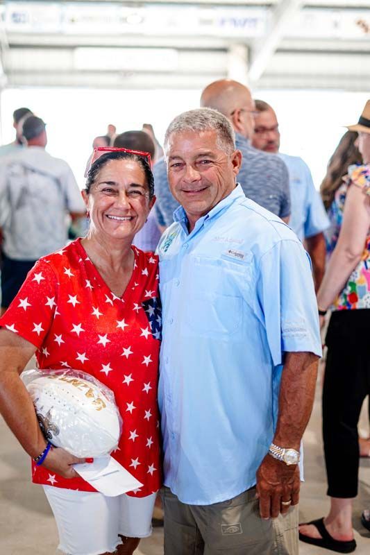 Smiling couple posing indoors, woman in red star dress holding white clutch, man in light blue shirt