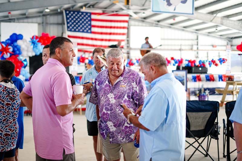 People chatting in a decorated hall with an American flag and red, white, and blue decorations.