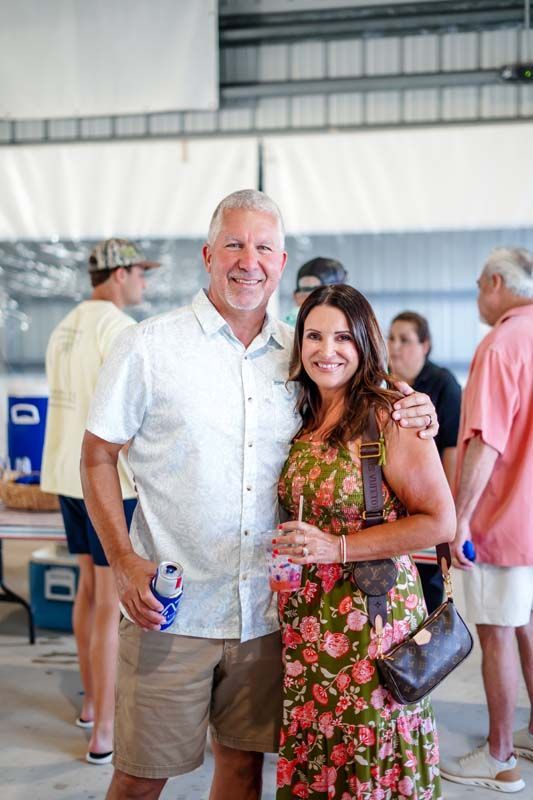Man and woman smiling at an indoor event, standing close and holding drinks.