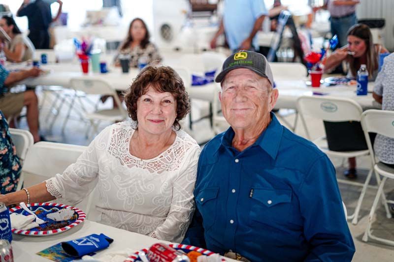 Couple seated at a banquet table, wearing patriotic red, white, and blue accessories.