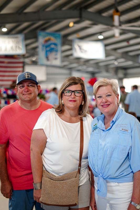 Three people standing together in a covered indoor market, smiling at the camera.