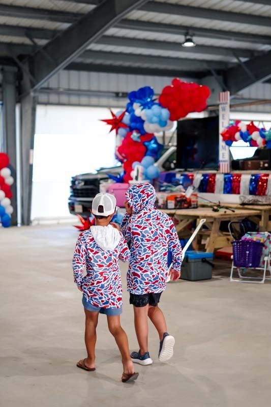 Two people in matching red, white, and blue outfits walk in a decorated indoor event space.