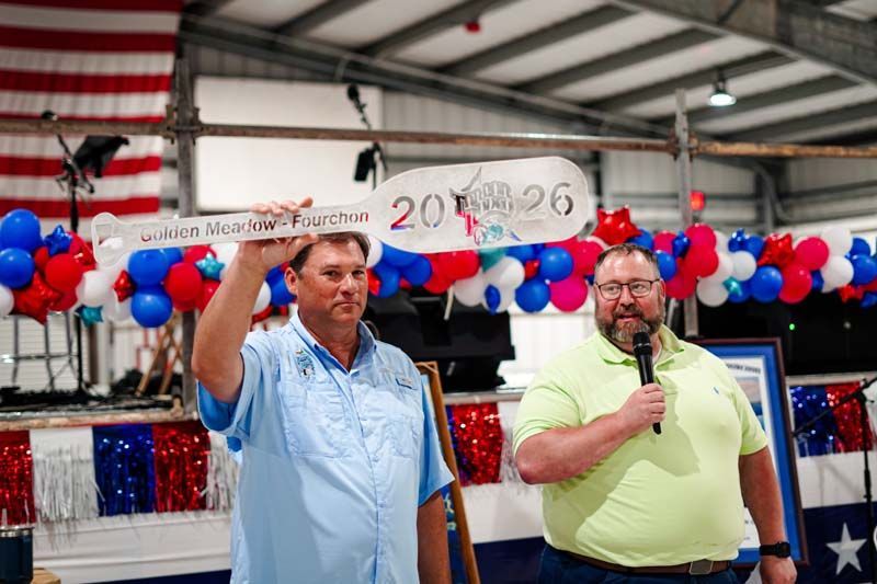 Two men speaking on a decorated stage with red, white, and blue balloons and a 2024 sign.