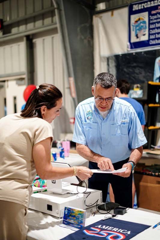 Two people reviewing a document at a table in a market stall or trade show booth.