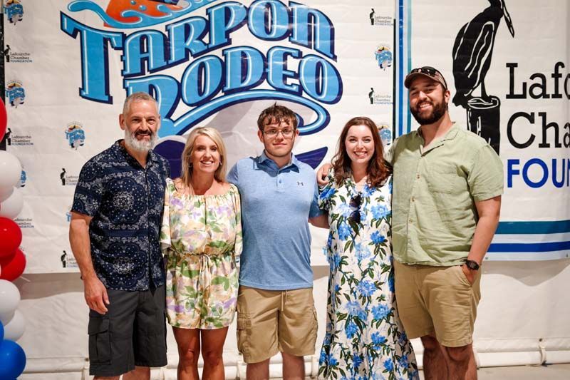 Five people posing in front of a Tarpon Rodeo banner at an event booth