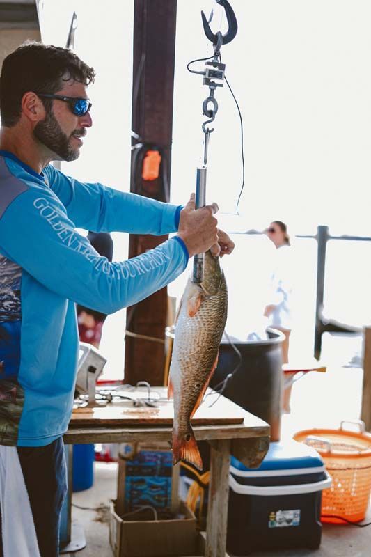 A man is holding a large fish on a hook.