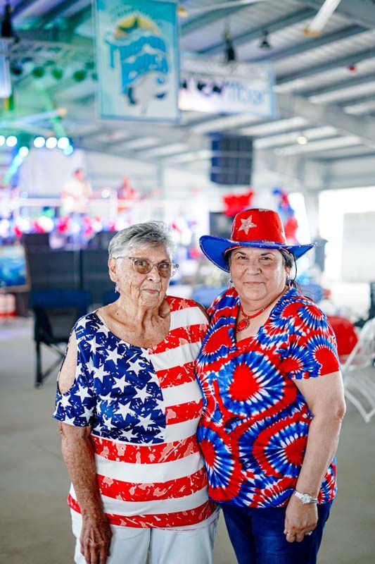 Two people in red, white, and blue patriotic outfits standing indoors at a sports venue