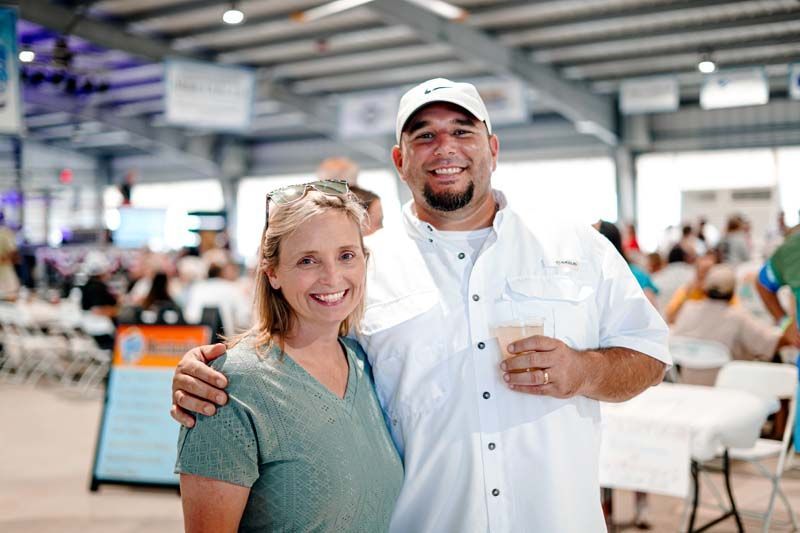 A man and a woman are posing for a picture in a crowded room.
