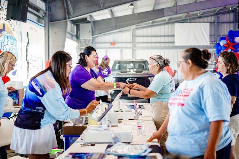 People at a volunteer food table handing out items in a bright indoor hall