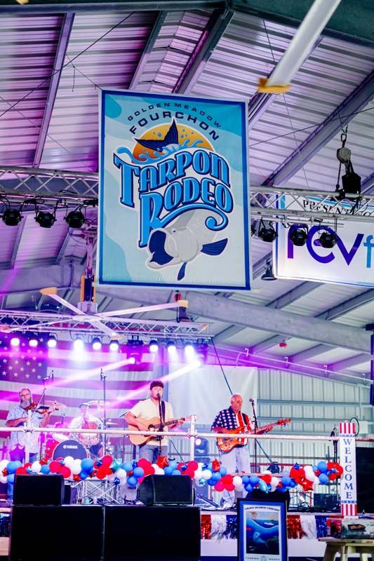Brightly lit indoor concert stage with performers, purple lights, and a large “Turbo Dodgers” sign overhead