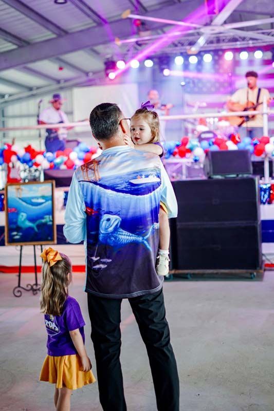 Man and child watching a live performance under purple stage lights in an indoor arena