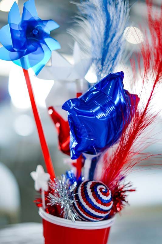 Red, white, and blue patriotic party favor with ribbon, stars, and spiral lollipop in a cup