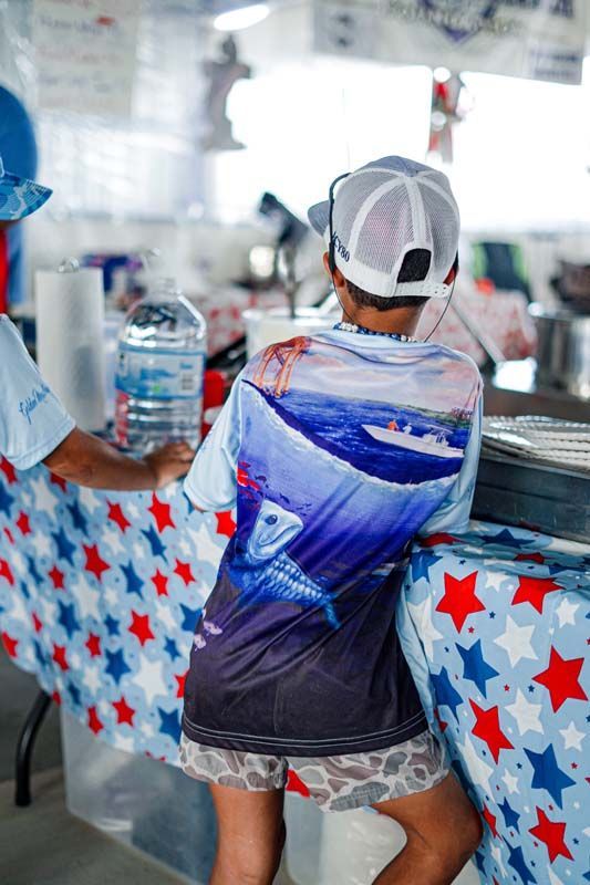 Person sitting at a counter with a red, white, and blue star-patterned cloth, holding a large bottle of water.