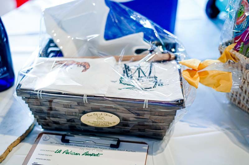 Wrapped gift basket with a white bow and oval label on a table, surrounded by blue and yellow decor